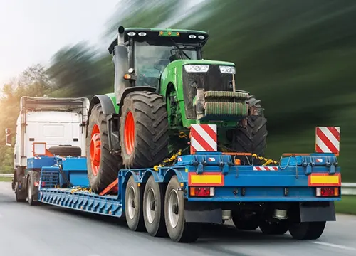 Flatbed trailer transporting oversized machinery across state highways.